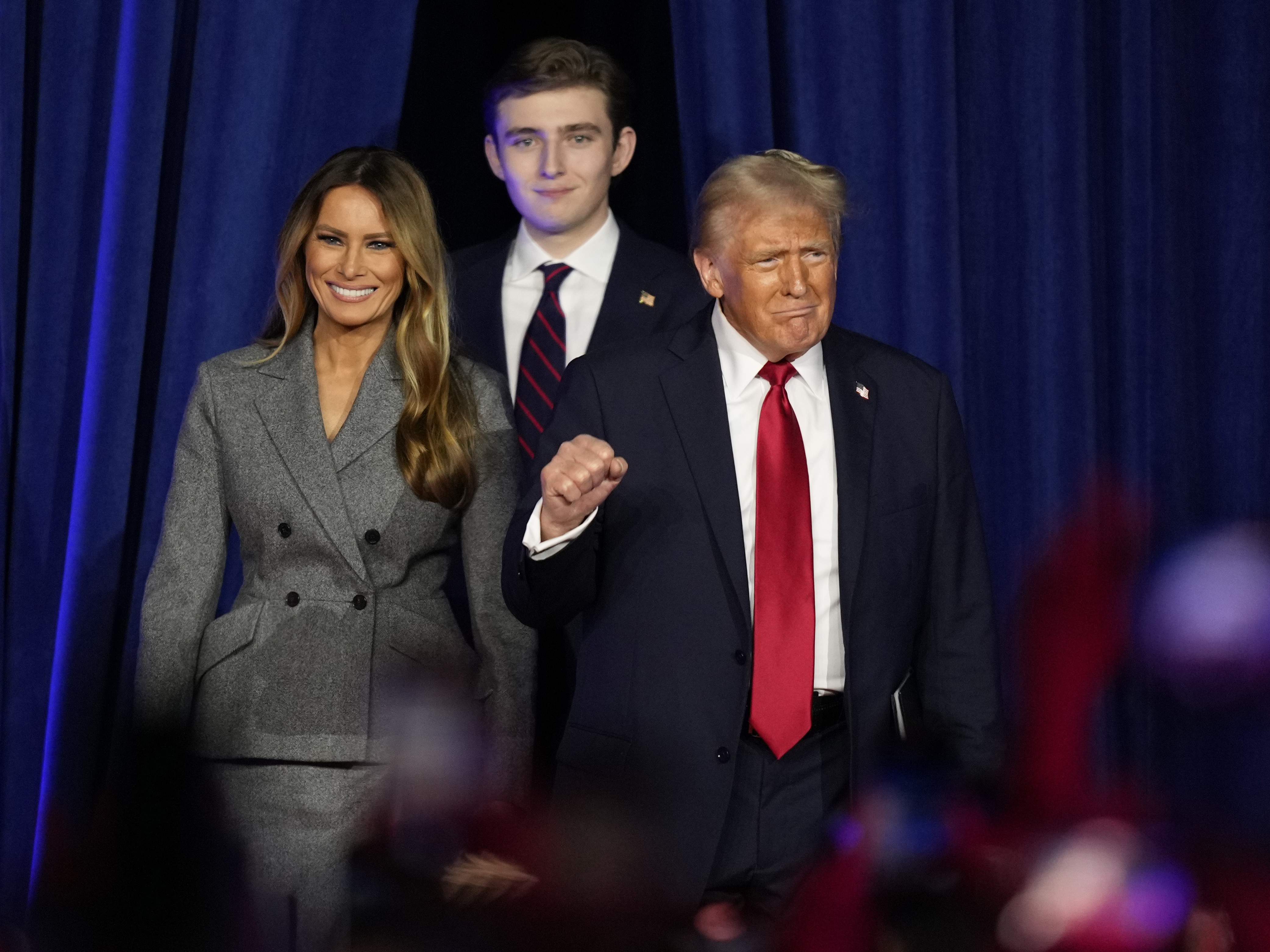 caption: Republican presidential nominee former President Donald Trump, joined by Melania Trump, left, and Barron Trump, arrives to speak at an election night watch party on Nov. 6, 2024, in West Palm Beach, Fla.