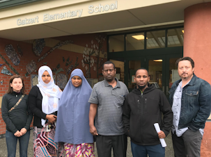caption: Bailey Gatzert Elementary parents Amalia Icreverzi, Nimco Ahmed, Aisha Mohamed, Abu Mohamed, Ali Abdulaziz and Jaime Griesemer stood outside the school on June 24, 2019.