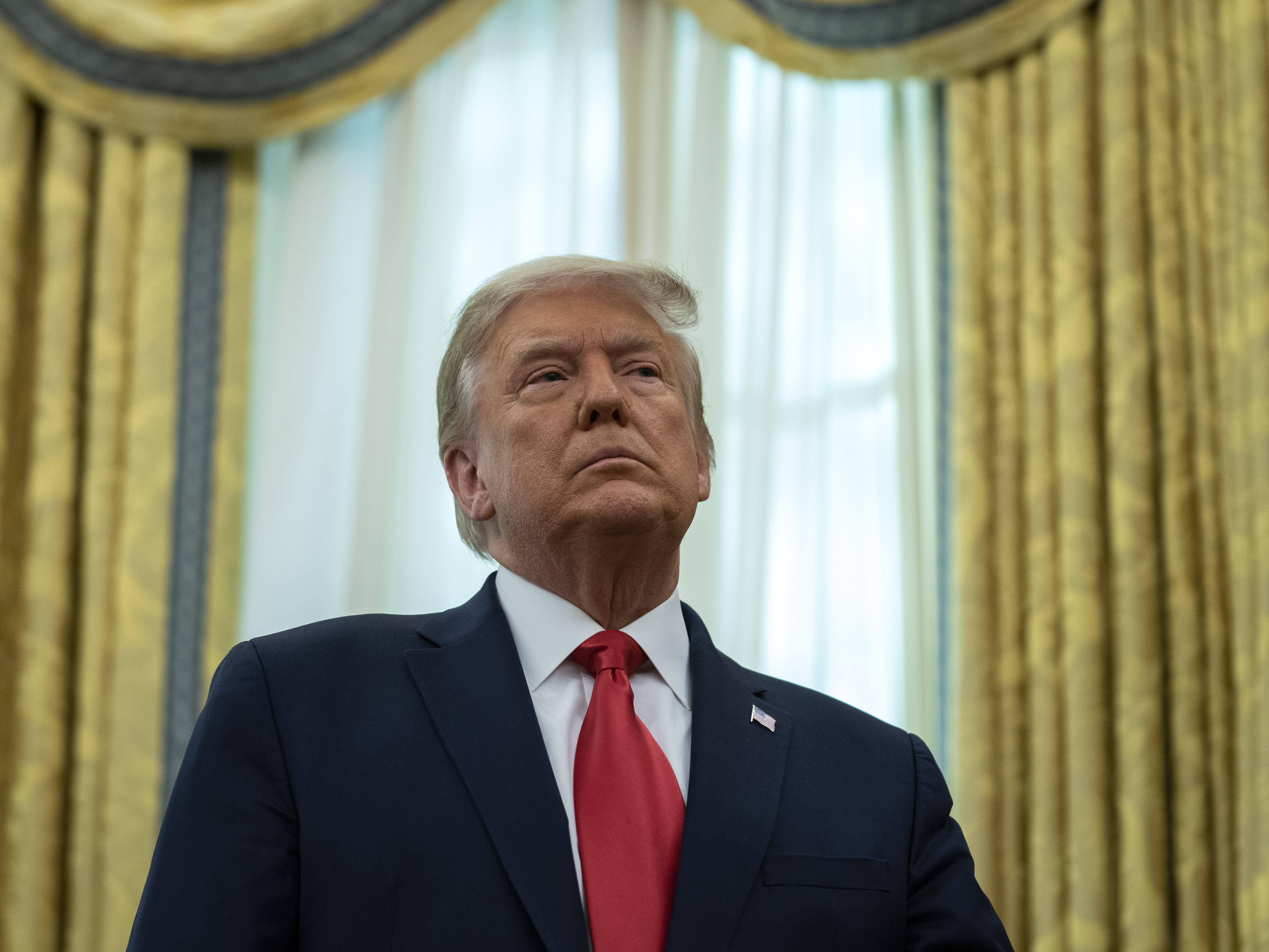 caption: President Trump listens during a ceremony Thursday to present the Presidential Medal of Freedom to former college football coach Lou Holtz in the Oval Office.