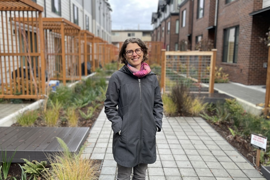 caption: Rachel Koller of Shift Zero, a consortium of climate advocacy groups that focuses on making buildings more efficient, seen outside townhomes with heat pumps in Seattle's Crown Hill neighborhood