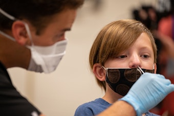 caption: A nurse tests a student for COVID-19 at Brandeis Elementary School in Louisville, Ky.