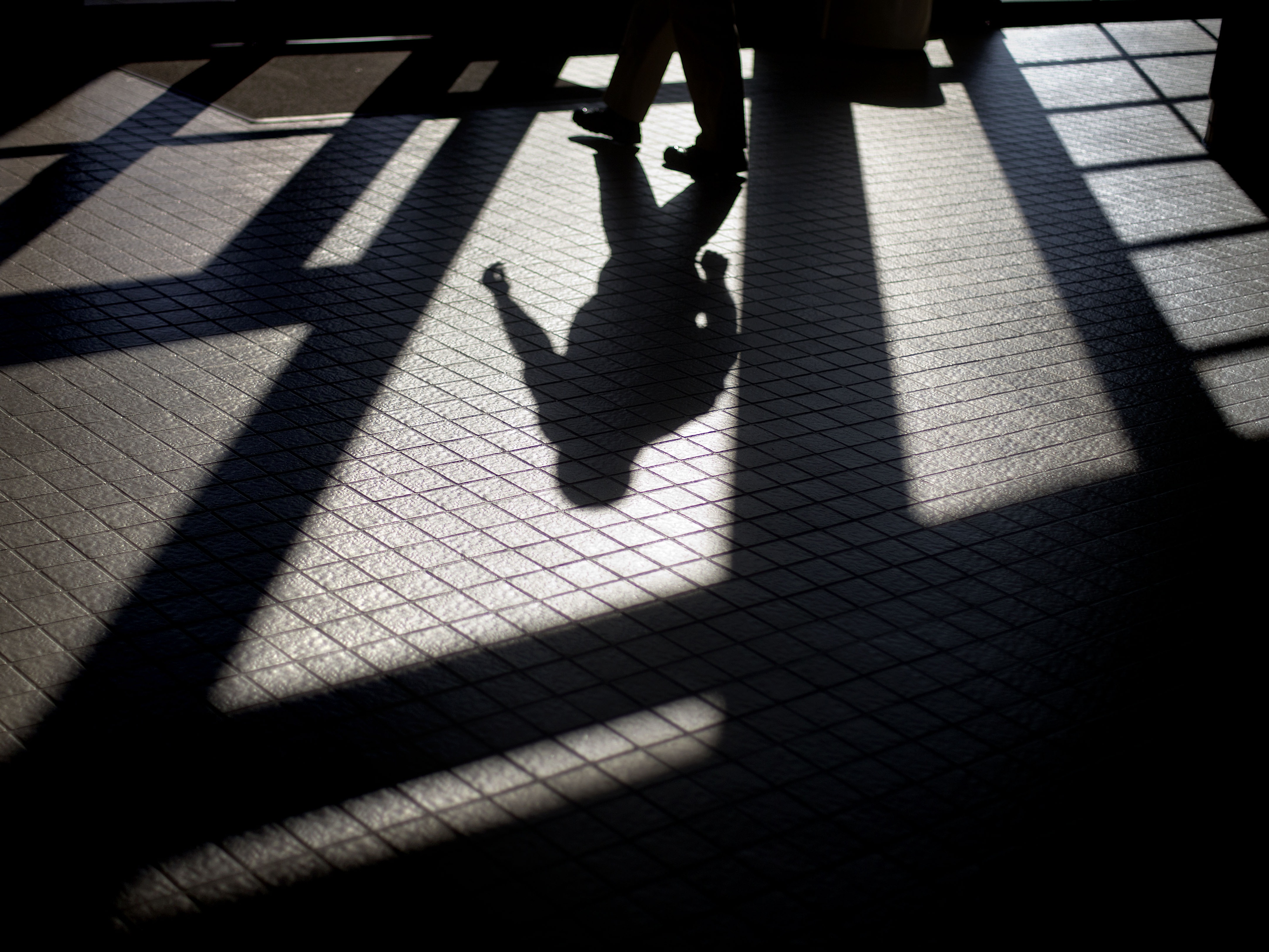 caption: In this 2012 photo, the shadow of a Georgia Department of Juvenile Justice correctional officer is cast as he leaves a training facility.