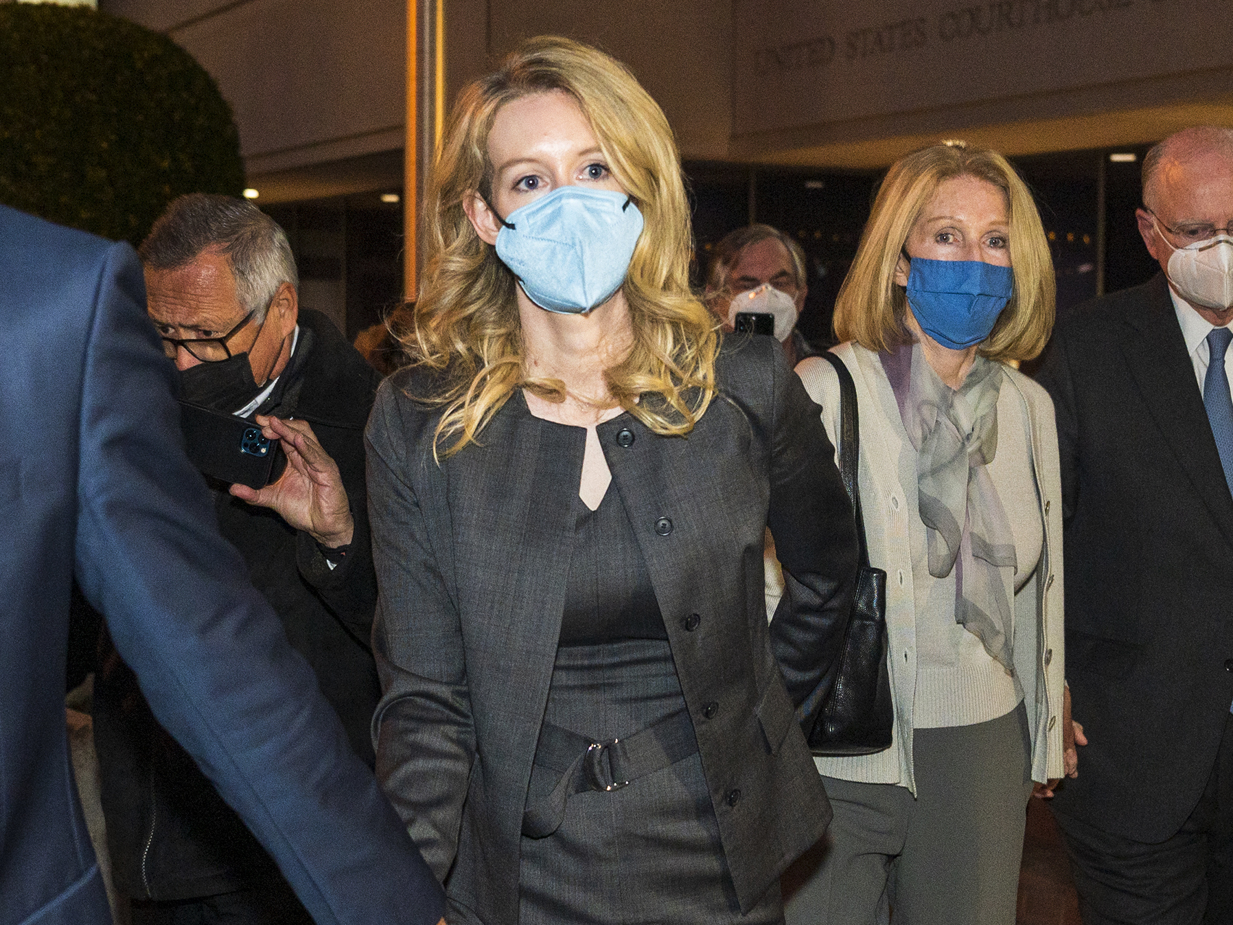 caption: Elizabeth Holmes, center, leaves federal court on Jan. 3 after her verdict in San Jose, Calif. A judge on Wednesday set her sentencing date for Sept. 26 following her conviction on fraud charges.