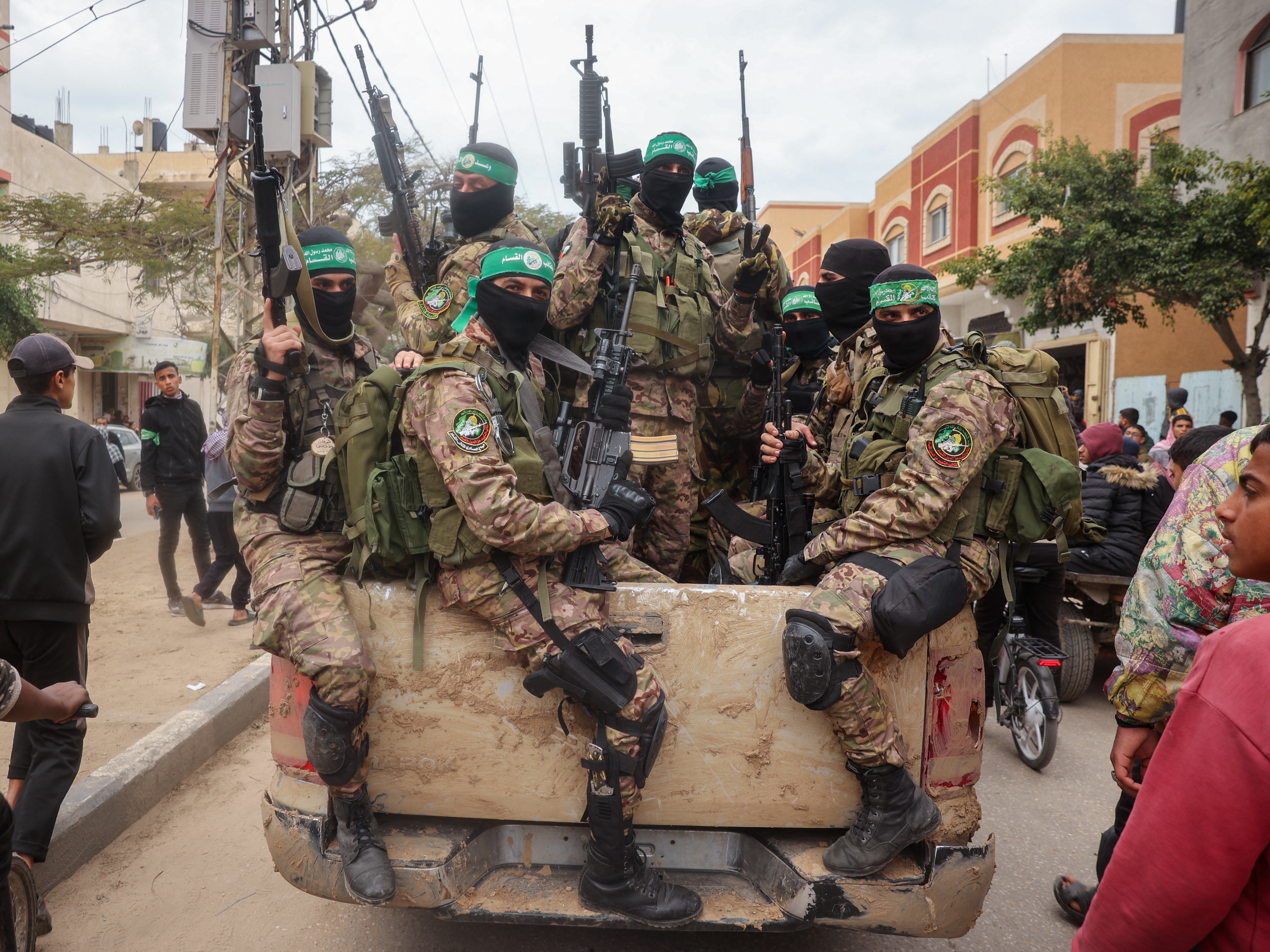 caption: Hamas fighters patrol a street before they hand over three Israeli hostages to a Red Cross team in Deir el-Balah, central Gaza, on Feb. 8.