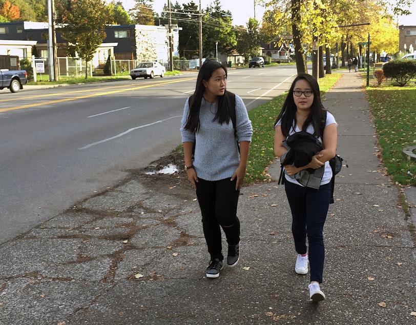 caption: Emily Au, right, a junior at Rainier Beach High School, walks home from school with her cousin, Rebecca Chung. Au says the walk is dangerous, and that some students skip class or show up tardy because they don't want to walk in the dark.