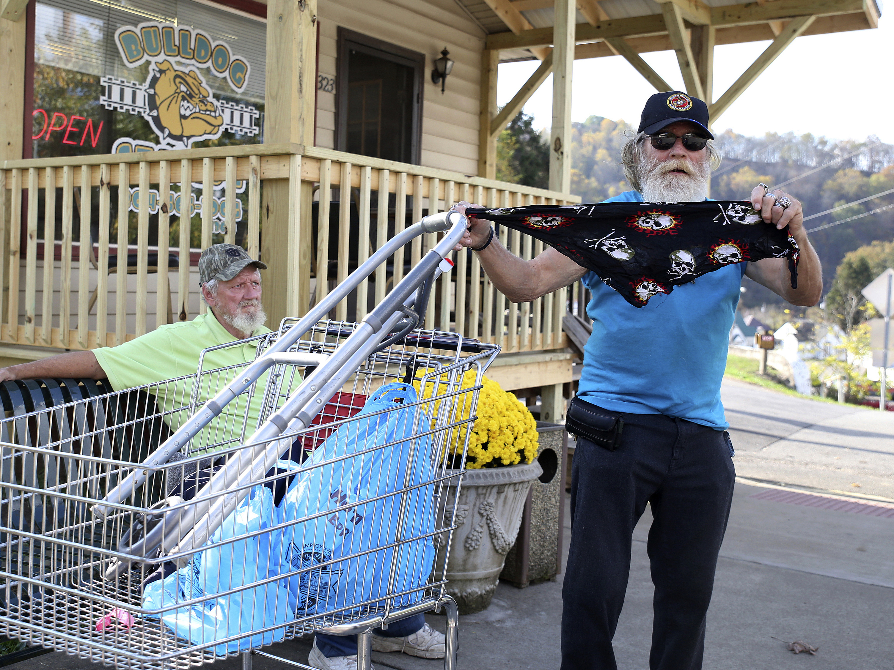 caption: A man displays his face covering for protection against the coronavirus in West Union, W.Va., last month. Small communities from the Dakotas to Kansas to West Virginia have recently seen coronavirus cases rising again.
