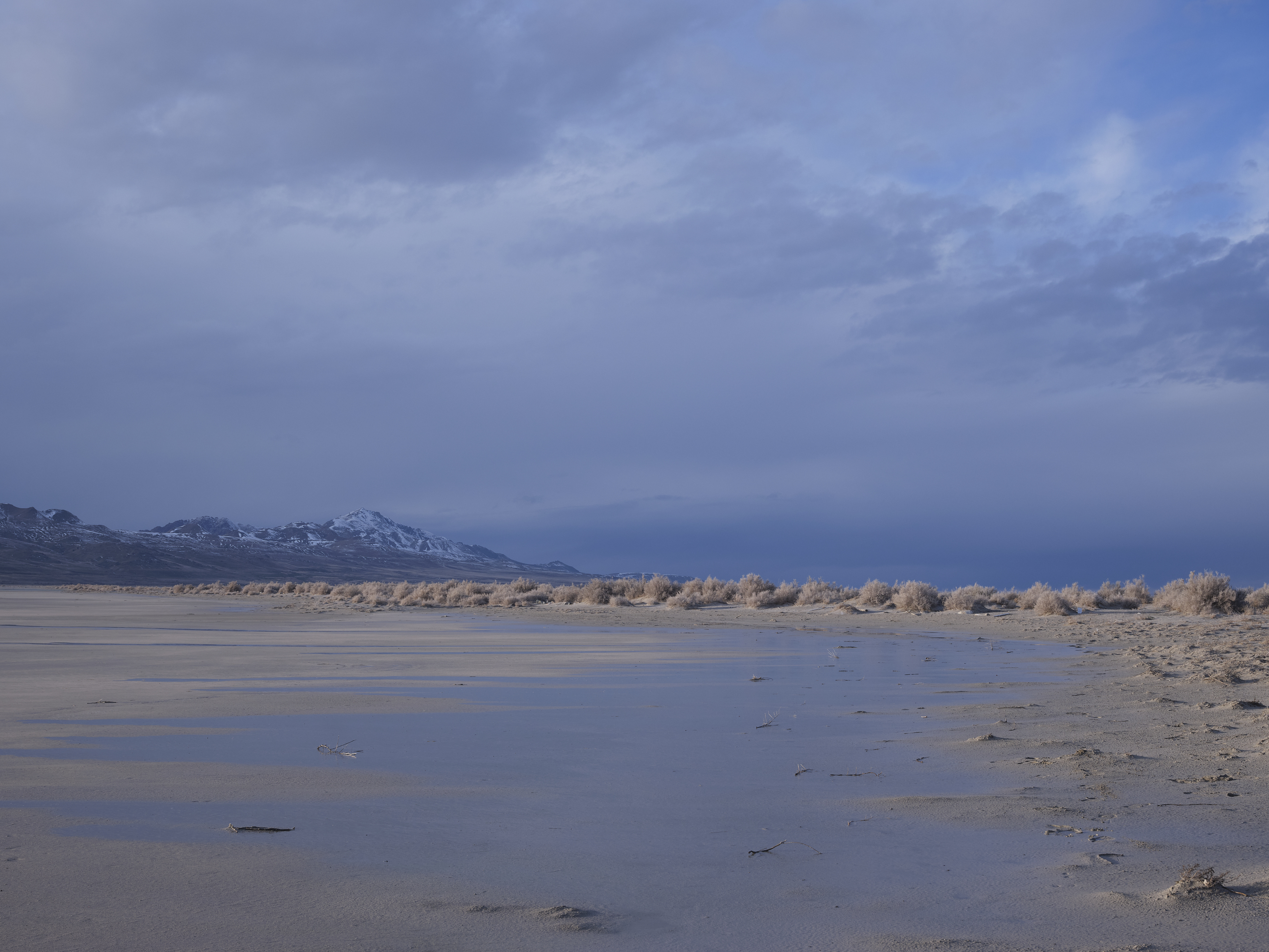 caption: Receding water in Utah's Great Salt Lake is seen on March 5. Environmentalists are suing the state to force water cutbacks to farmers to save the Great Salt Lake.