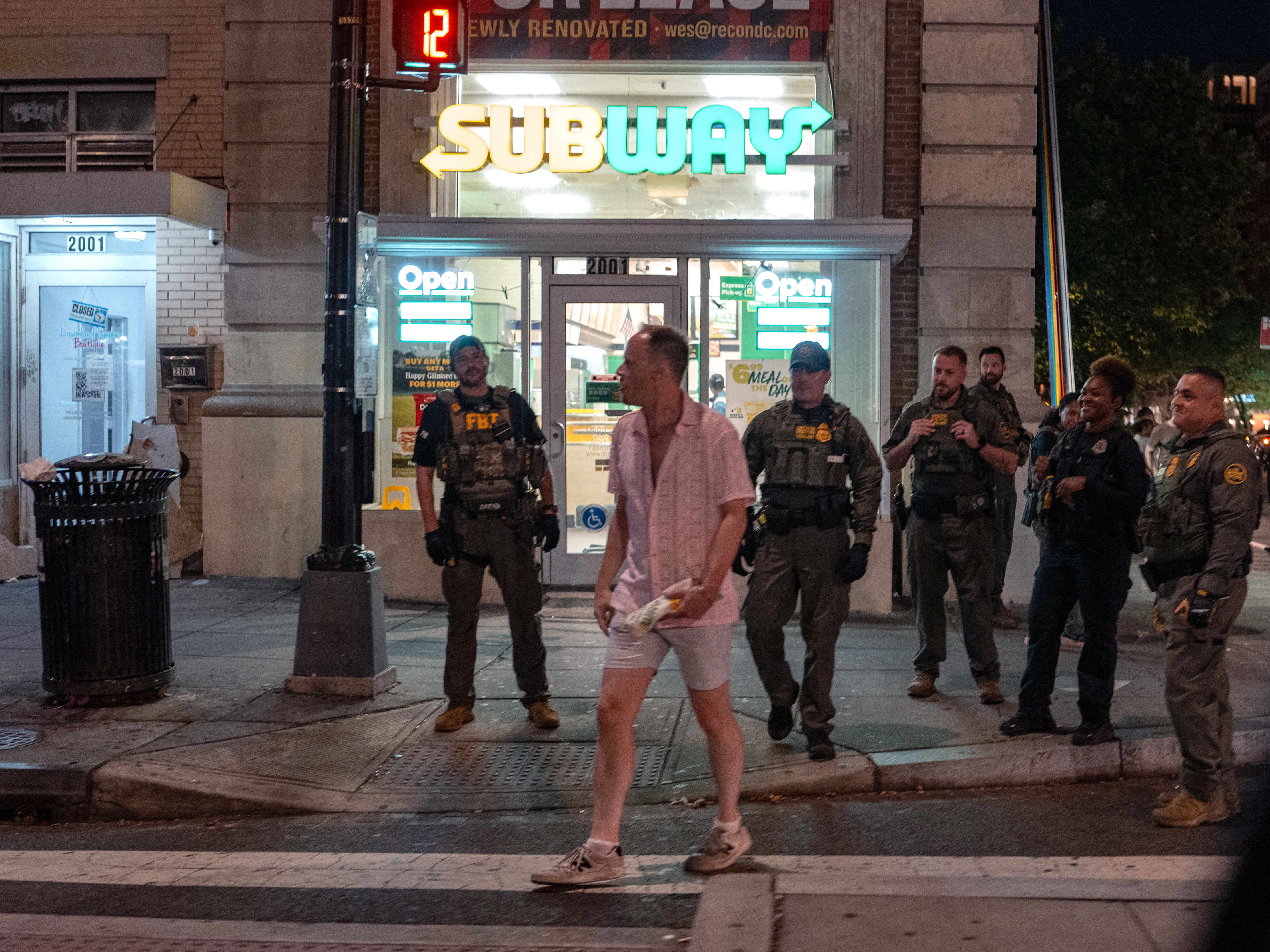 caption: FBI and Border Patrol officers speak with Sean Charles Dunn, after he threw his sandwich at an officer, along the U Street corridor during a federal law enforcement deployment to the nation's capital on August 10, 2025 in Washington, D.C.