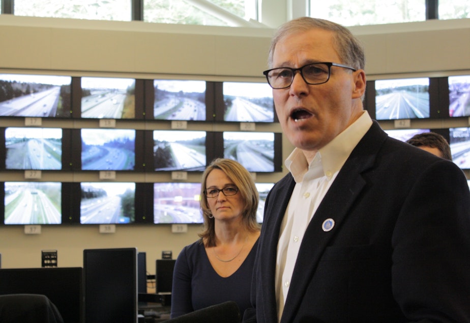 caption: Washington Governor Jay Inslee stands before a wall of traffic monitors at a state transportation management center with Patty Rubstello, WSDOT's Assistant Secretary for Tolling