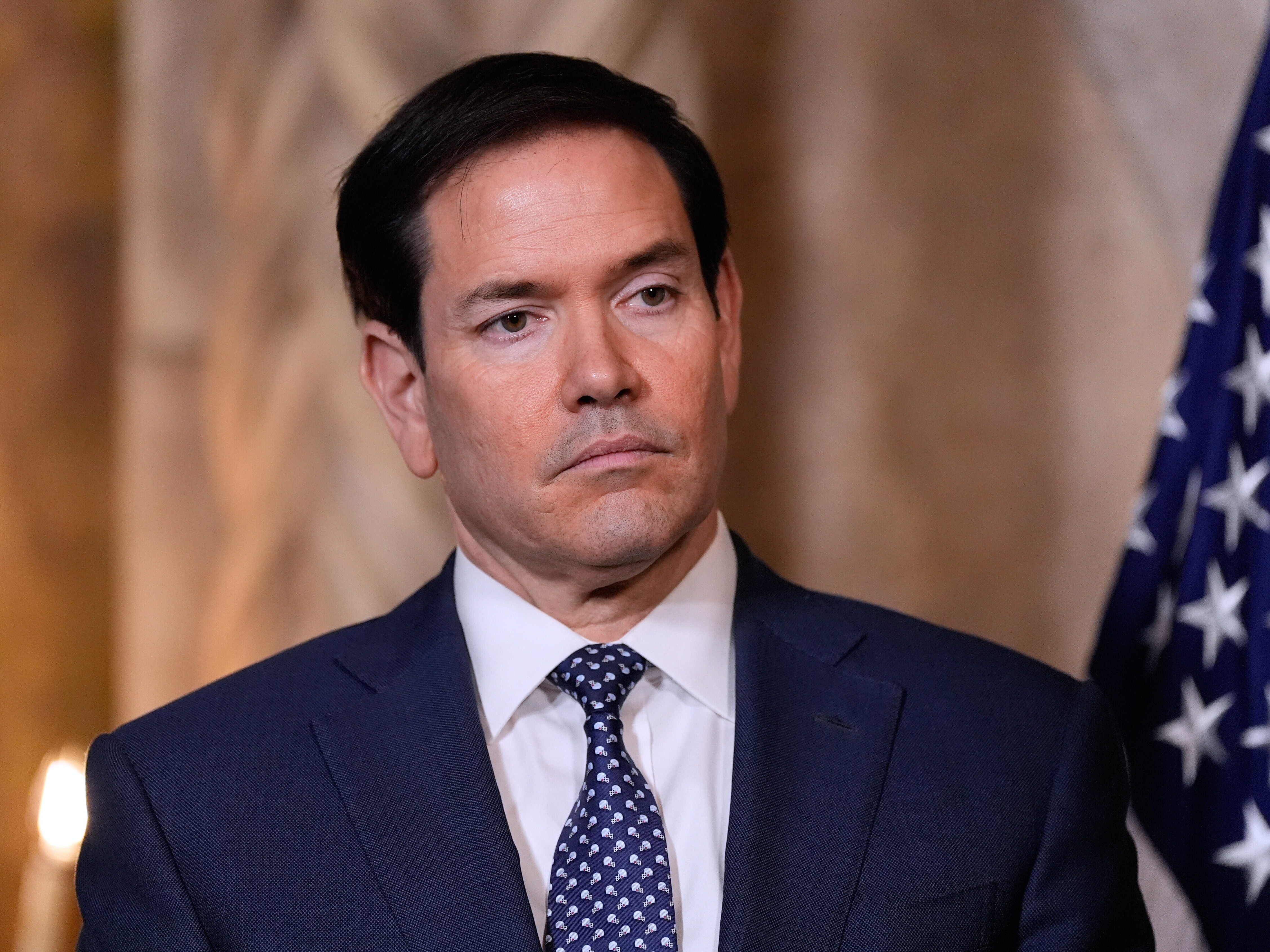 caption: Secretary of State Marco Rubio listens as President Donald Trump speaks at his Mar-a-Lago club, Monday, Dec. 22, 2025, in Palm Beach, Fla.