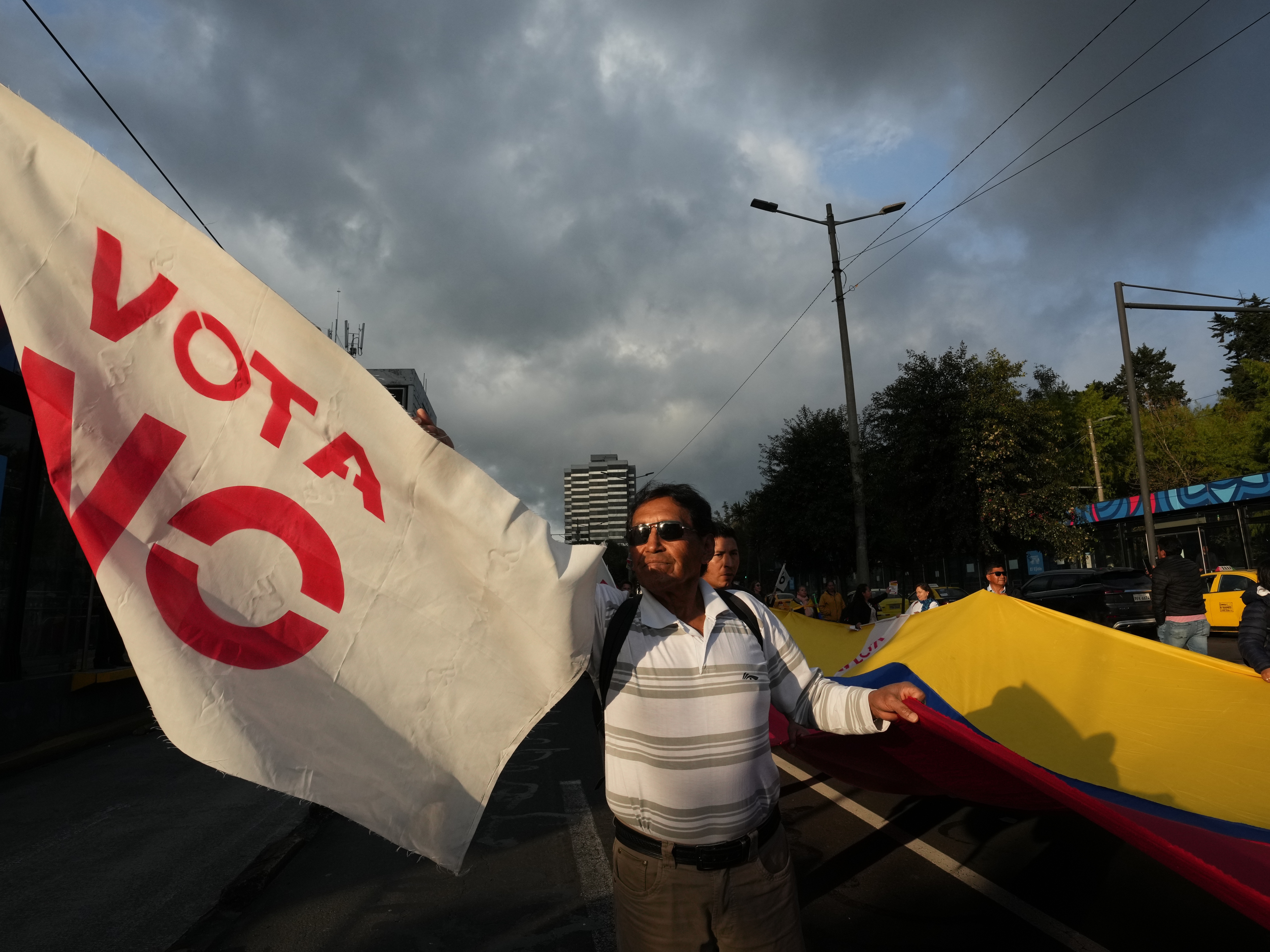 caption: Demonstrators encourage passersby to vote against a referendum to decide, among other items, whether to allow foreign military bases in Ecuador, during a rally in Quito, Wed. Nov. 12, 2025. In the end, the no vote won.
