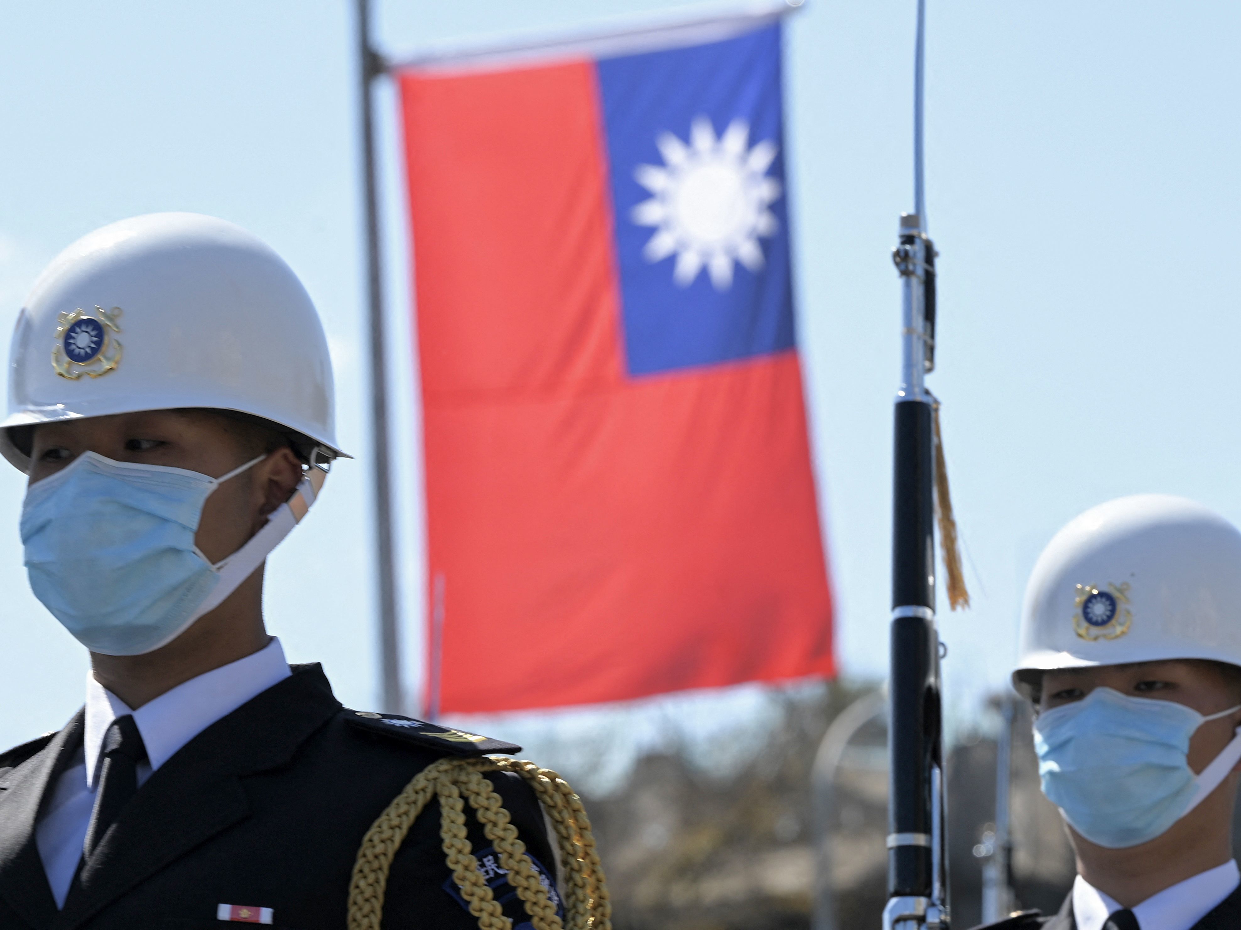 caption: Taiwanese honor guards stand by under a national flag during a military ceremony in front of the presidential office in Taipei on March 9.