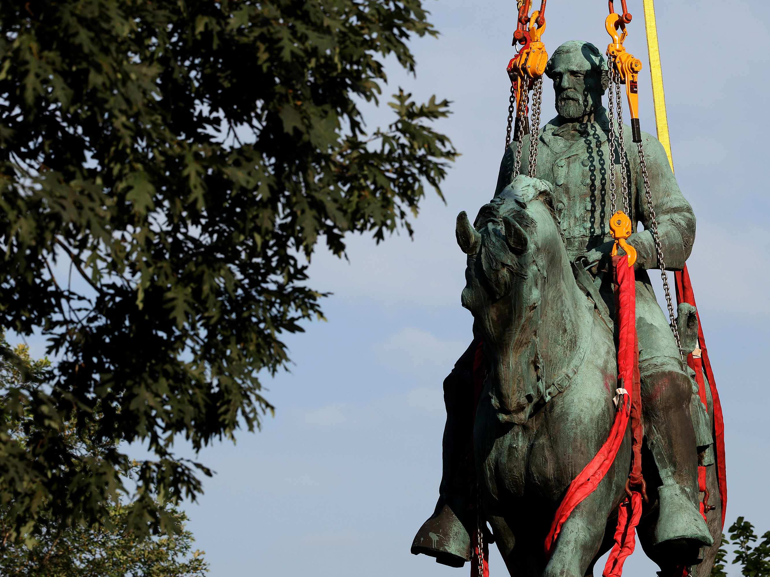 caption: Workers remove a statue of Confederate General Robert E. Lee from Market Street Park July 10, 2021 in Charlottesville, Virginia. Initial plans to remove the statue four years ago sparked the infamous "Unite the Right" rally where 32-year-old Heather Heyer was killed.