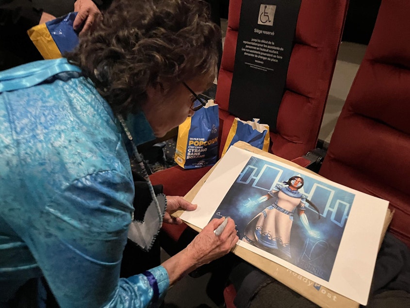 caption: Cecelia King signs fan art made by her writer-artist nephew Arihhonni. (Monica Sandreczki/NCPR)