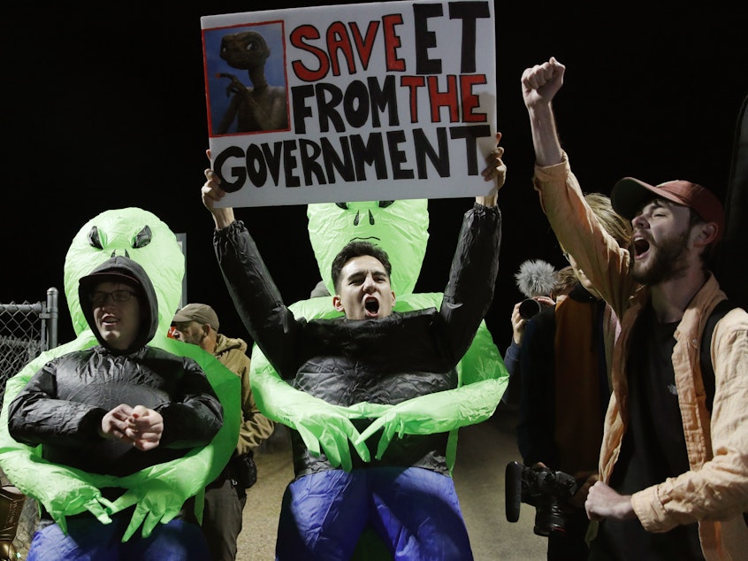 caption: Mario Rayna, center, chants with others at an entrance to the Nevada Test and Training Range near Area 51.