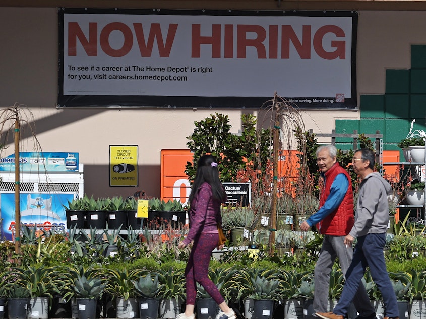 caption: Hiring accelerated in the U.S. in March, adding 303,000 jobs, according to a report from the Bureau of Labor Statistics. The unemployment rate dipped to 3.8%, staying under 4% for more than two full years. People walk past a Home Depot in San Rafael, Calif.