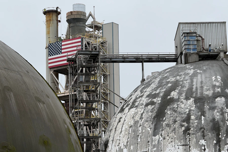 Caption: Ash Grove Cement workers, barely visible, stand atop a cooling tower at a Seattle cement plant on March 18, 2026.