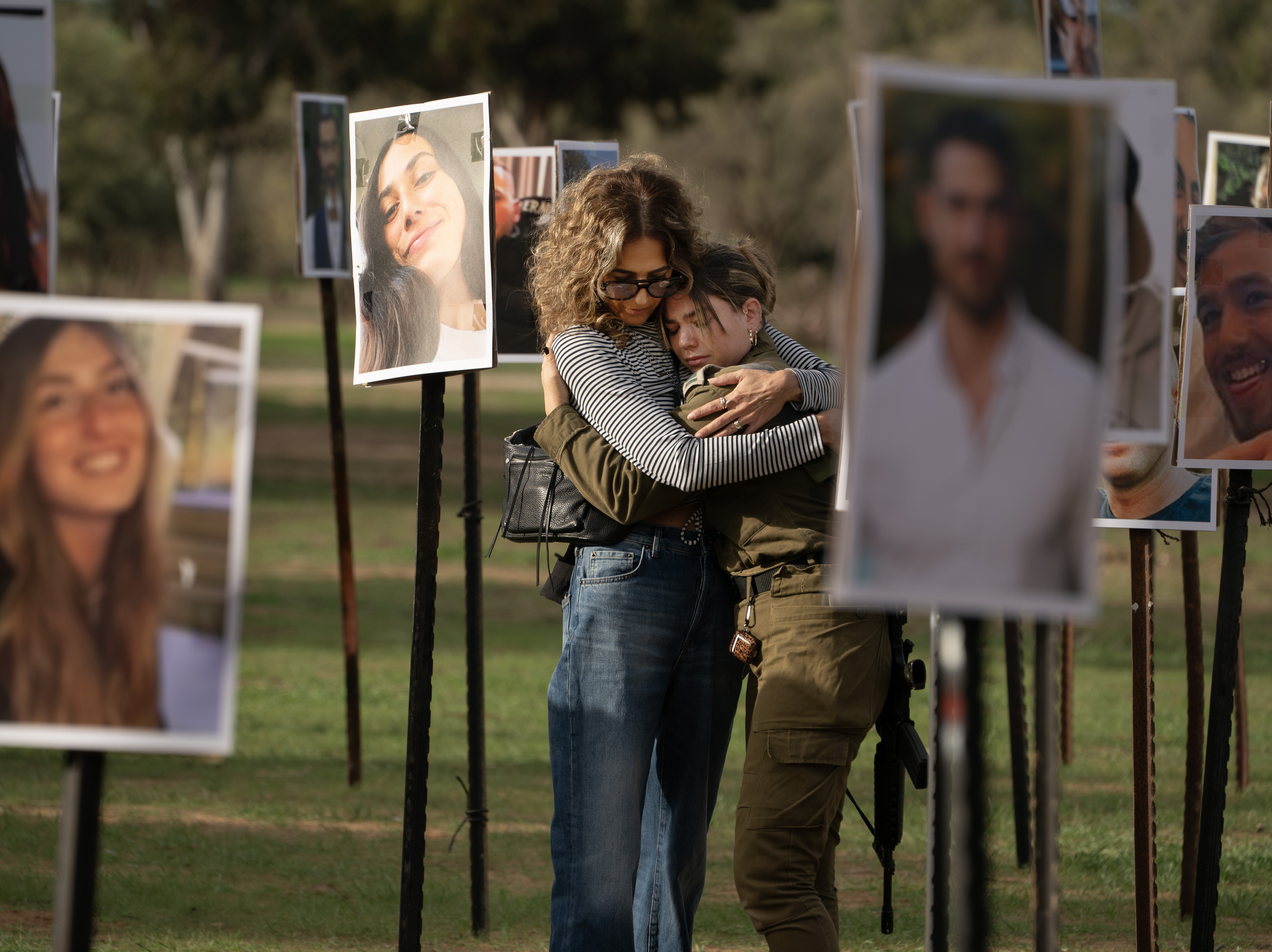 caption: Sigal Manzuri, whose daughters Norelle and Roya were killed in the Hamas-led attack on the Nova music festival on Oct. 7, embraces one of their friends. Surrounding them are photos of people killed and taken hostage by Hamas militants, displayed at the site as DJs spin music to commemorate victims, near Kibbutz Re'im, Tuesday.