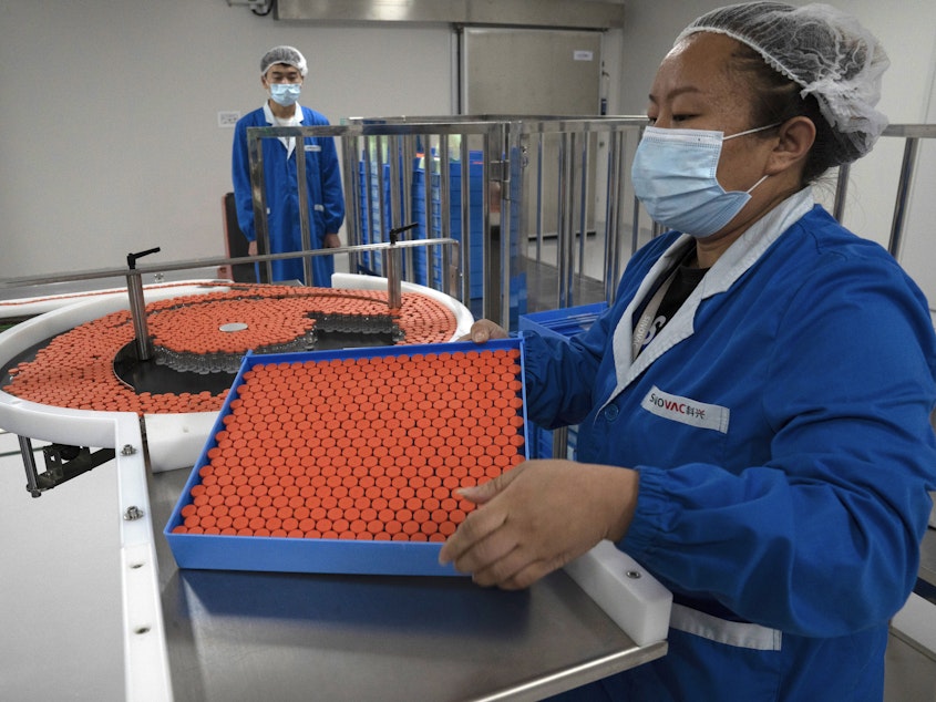 caption: A worker feeds vials for production of a vaccine for COVID-19 at the SinoVac vaccine factory in Beijing. China said on Friday that it is joining the COVID-19 vaccine alliance known as COVAX.