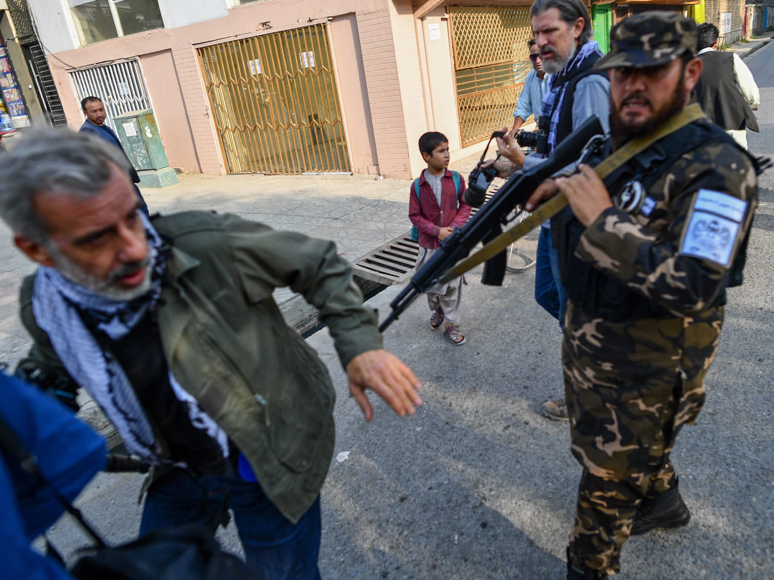 caption: A member of the Taliban special forces pushes a journalist covering a demonstration by women protesters in Kabul on Sept. 30.