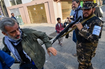 caption: A member of the Taliban special forces pushes a journalist covering a demonstration by women protesters in Kabul on Sept. 30.