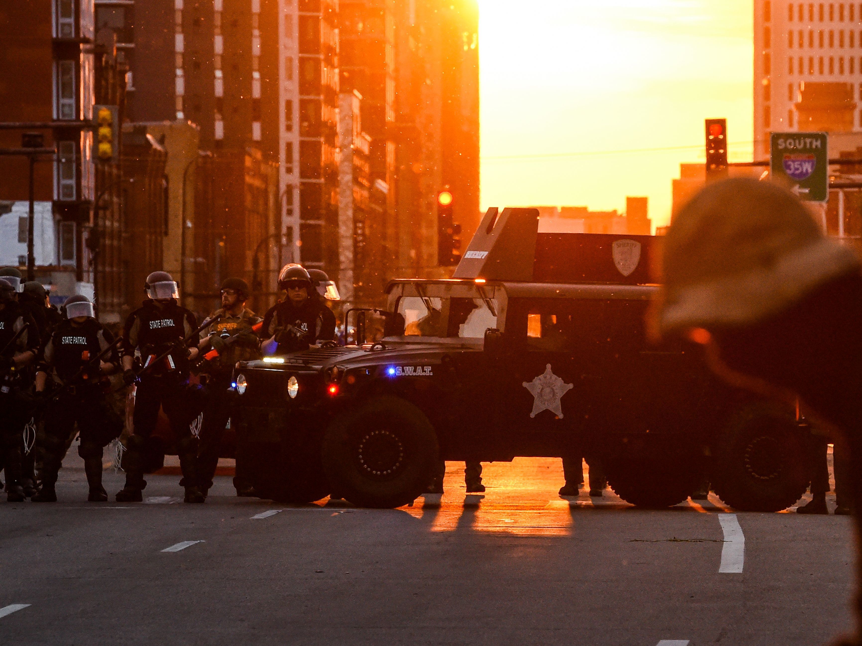 caption: Police officers take guard during a protest over the death of George Floyd last month in Minneapolis.