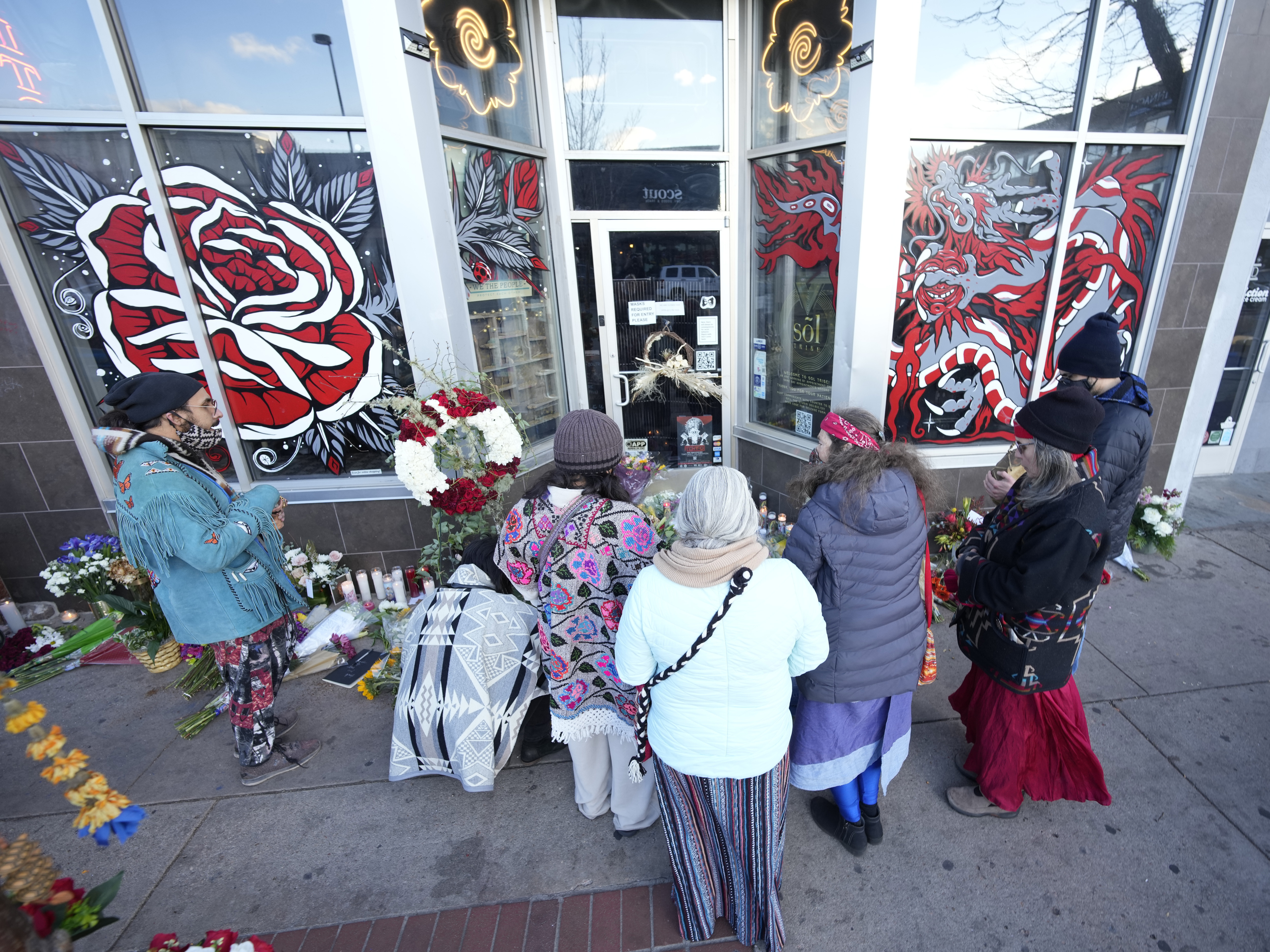 caption: Mourners gather outside the door of a tattoo parlor in Denver on Tuesday, one of the scenes of a shooting rampage the day prior that left six people dead —including the suspected shooter — and left two more people wounded.
