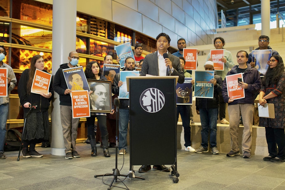 caption: Samir Khobragade explains how his family has fought against caste discrimination in India, and hopes to address it here. City Councilmember Kshama Sawant (far right) held a press conference Tuesday to announce legislation that would ban caste-based discrimination in Seattle.