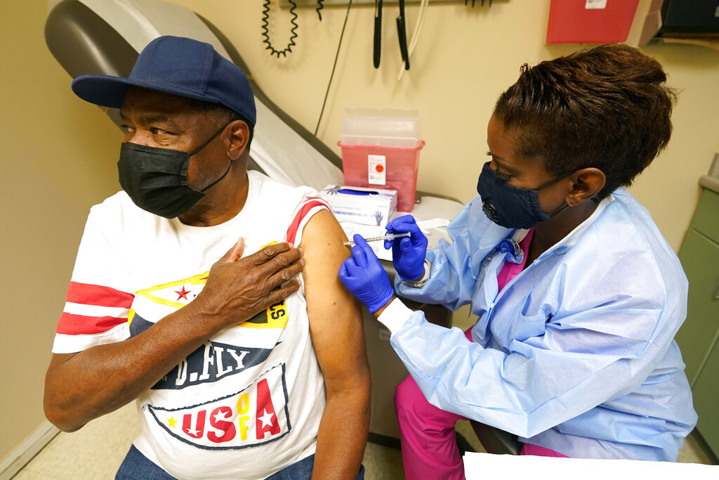 caption: Wilbert Marshall, 71, looks away while receiving the COVID-19 vaccine from Melissa Banks, right, a nurse at the Aaron E. Henry Community Health Service Center in Clarksdale, Miss., Wednesday, April 7, 2021. Marshall was among a group of seniors from the Rev. S.L.A. Jones Activity Center for the Elderly who received their vaccinations. The Mississippi Department of Human Services is in the initial stages of teaming up with community senior services statewide to help older residents get vaccinated. (AP Photo/