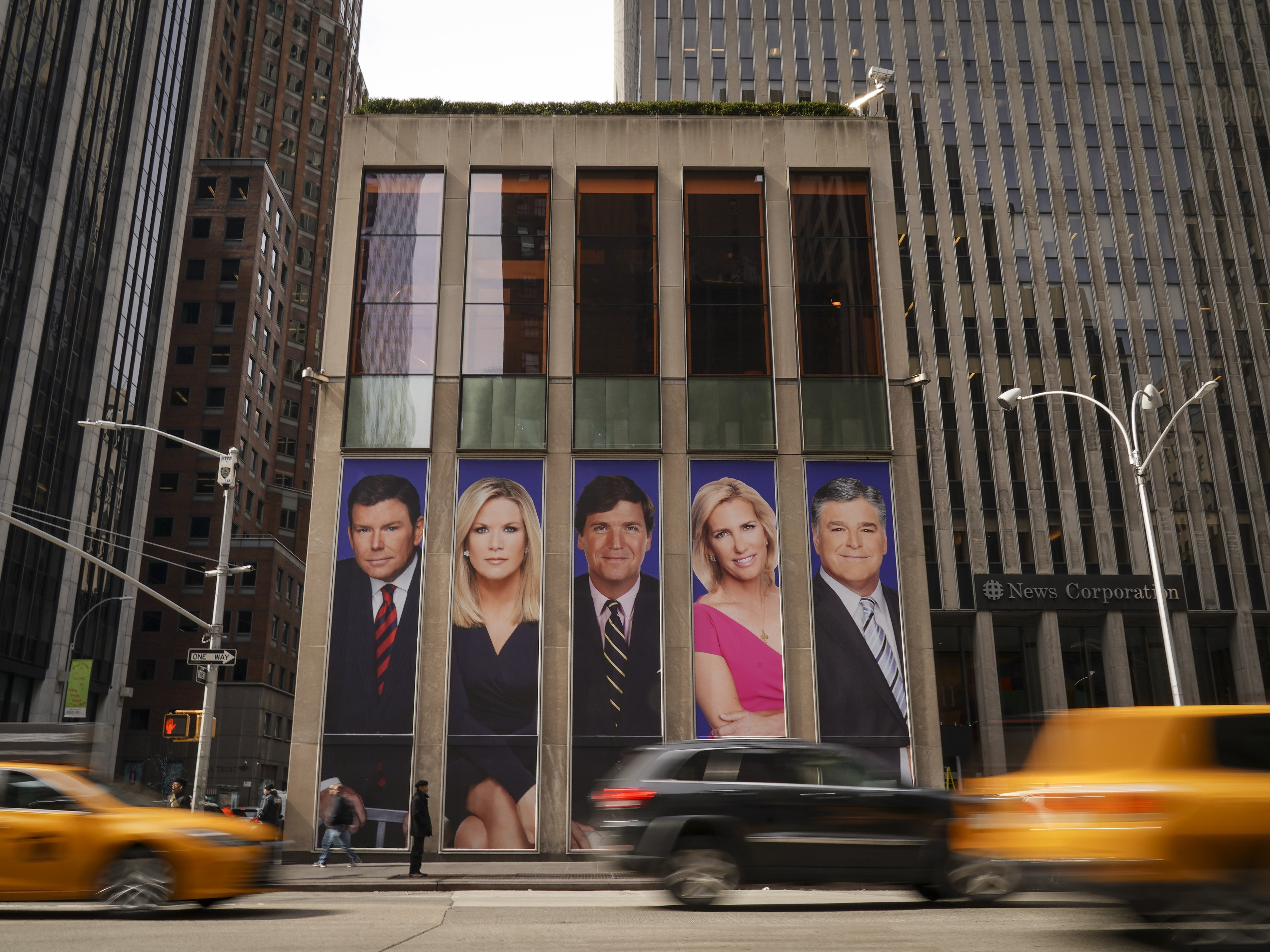 caption: Fox News personalities adorn the front of the News Corporation building in 2019 in New York City.
