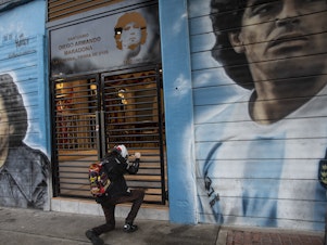 caption: A man prays in front of a sanctuary for the late soccer star Diego Maradona at Argentinos Juniors stadium in Buenos Aires, Argentina, last November.