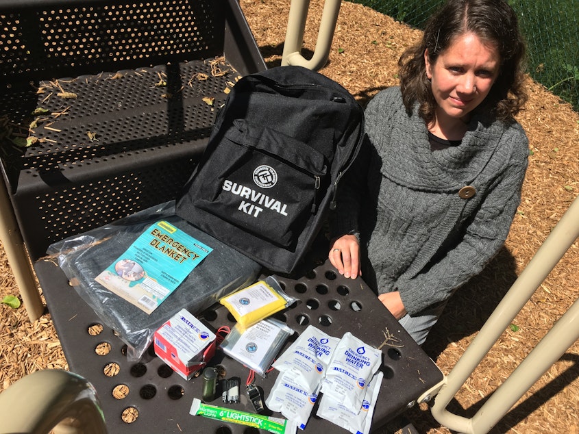 caption: Cannon Beach Academy director Amy Fredrickson with one of the school's 55 survival kits.