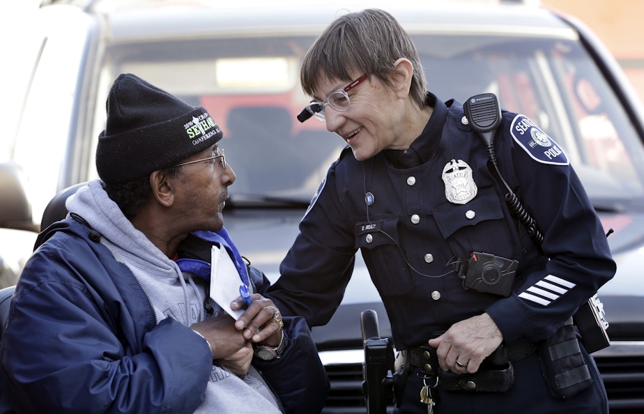 caption: In this March 12, 2015, file photo, Seattle police officer Debra Pelich, right, wears a video camera on her eyeglasses as she talks with Alex Legesse before a small community gathering in Seattle. 