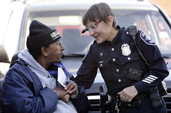 caption: In this March 12, 2015, file photo, Seattle police officer Debra Pelich, right, wears a video camera on her eyeglasses as she talks with Alex Legesse before a small community gathering in Seattle. 