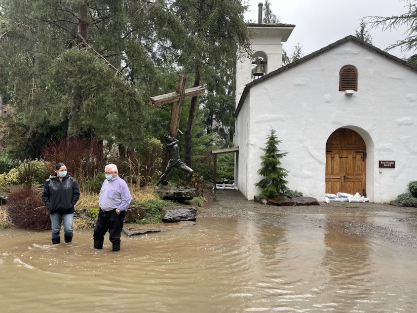 caption: As floodwaters recede, Narissa Burton and Bernard Garbusjuk inspect the grounds of their chocolate factory, Boehm's Candies. Here, they stand outside the chapel (with a small replica of the Sistine Chapel ceiling inside) where many couples get married.