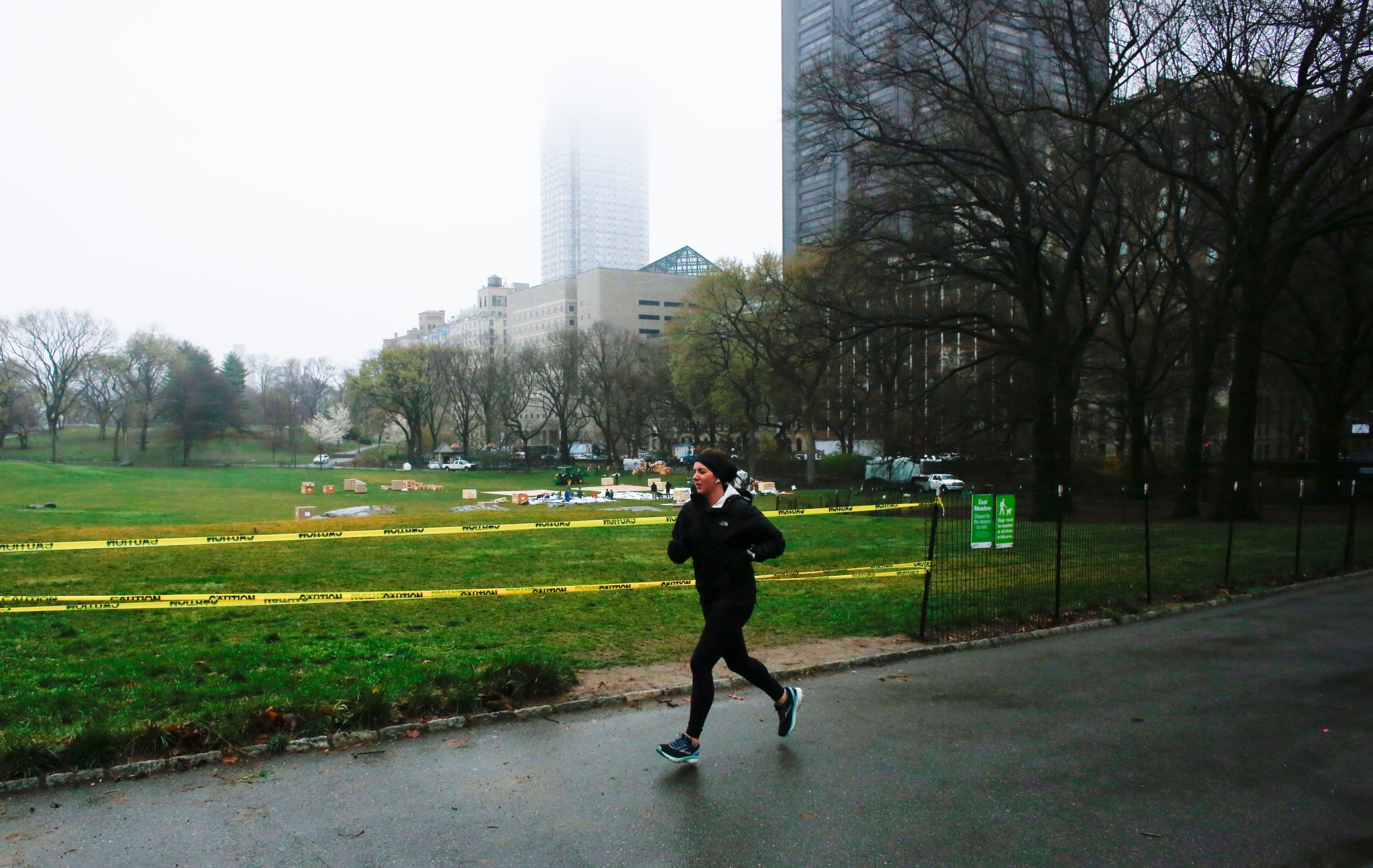 caption: A woman jogs by Central Park as workers set up a field hospital in front of Mount Sinai West Hospital on March 29, 2020 in New York City. (KENA BETANCUR/AFP via Getty Images)