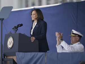 caption: Vice President Kamala Harris speaks at the graduation and commission ceremony at the U.S. Naval Academy in Annapolis, Md. The 63rd Superintendent of the US Naval Academy, Vice Admiral Sean S. Buck, is right.