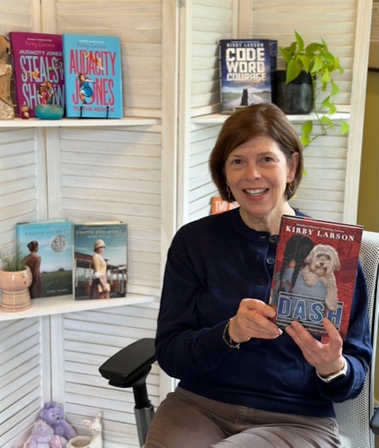 caption: Author Kirby Larson poses with her historical fiction novel "Dash." "Dash" has been challenged in the state of Florida. 