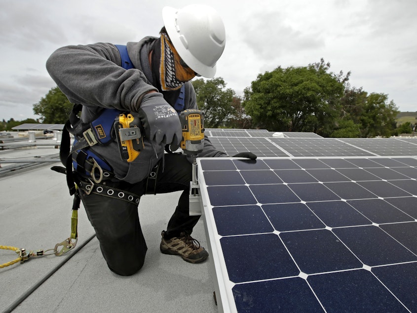caption: Gen Nashimoto, of Luminalt, installs solar panels in Hayward, Calif., on Wednesday, April 29, 2020.