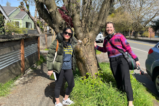 caption: KUOW's Paige Browning (right) with Taha Ebrahimi, author of "Street Trees of Seattle," in front of a golden chain tree in south Seattle. 