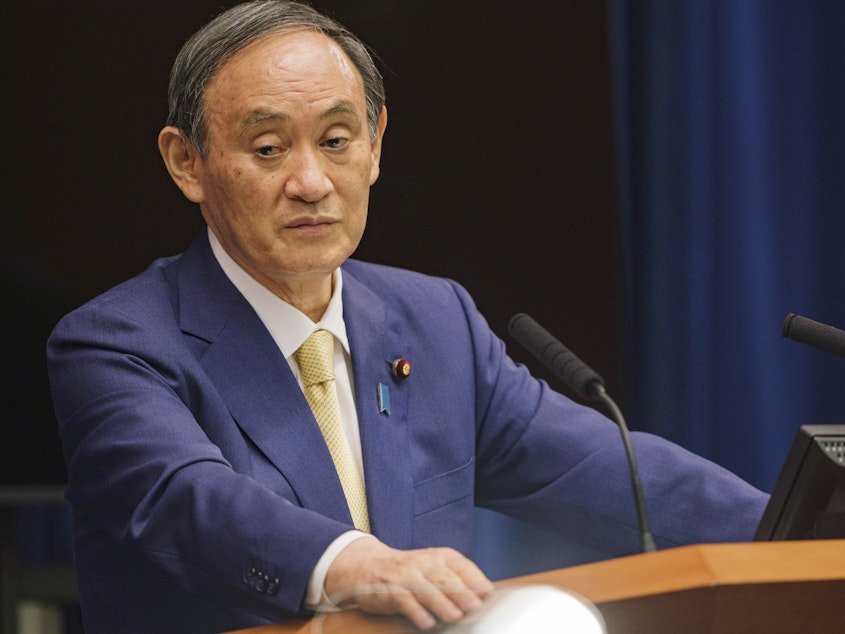 caption: Japan's Prime Minister Yoshihide Suga will extend a state of emergency to four more regions due to rising COVID-19 infections. Here, Suga speaks during a news conference on July 8.