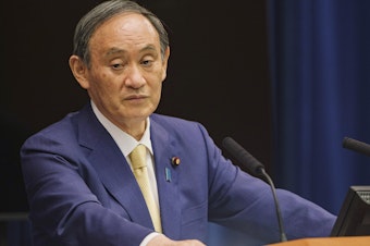 caption: Japan's Prime Minister Yoshihide Suga will extend a state of emergency to four more regions due to rising COVID-19 infections. Here, Suga speaks during a news conference on July 8.