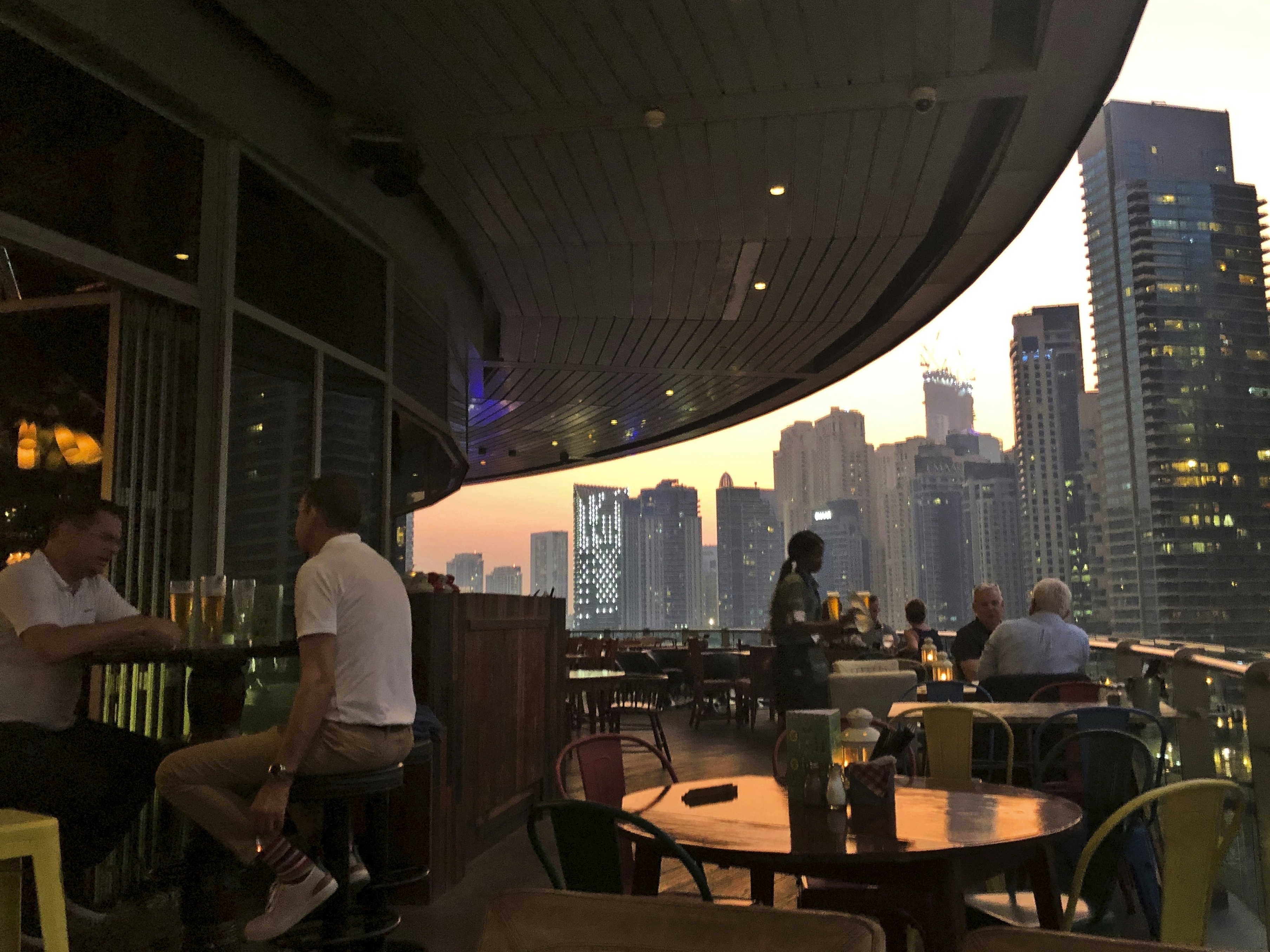 caption: People enjoy drinks at a restaurant overlooking the Marina district in Dubai, United Arab Emirates, in 2019. The country is loosening its liquor laws and other restrictions.
