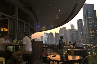 caption: People enjoy drinks at a restaurant overlooking the Marina district in Dubai, United Arab Emirates, in 2019. The country is loosening its liquor laws and other restrictions.