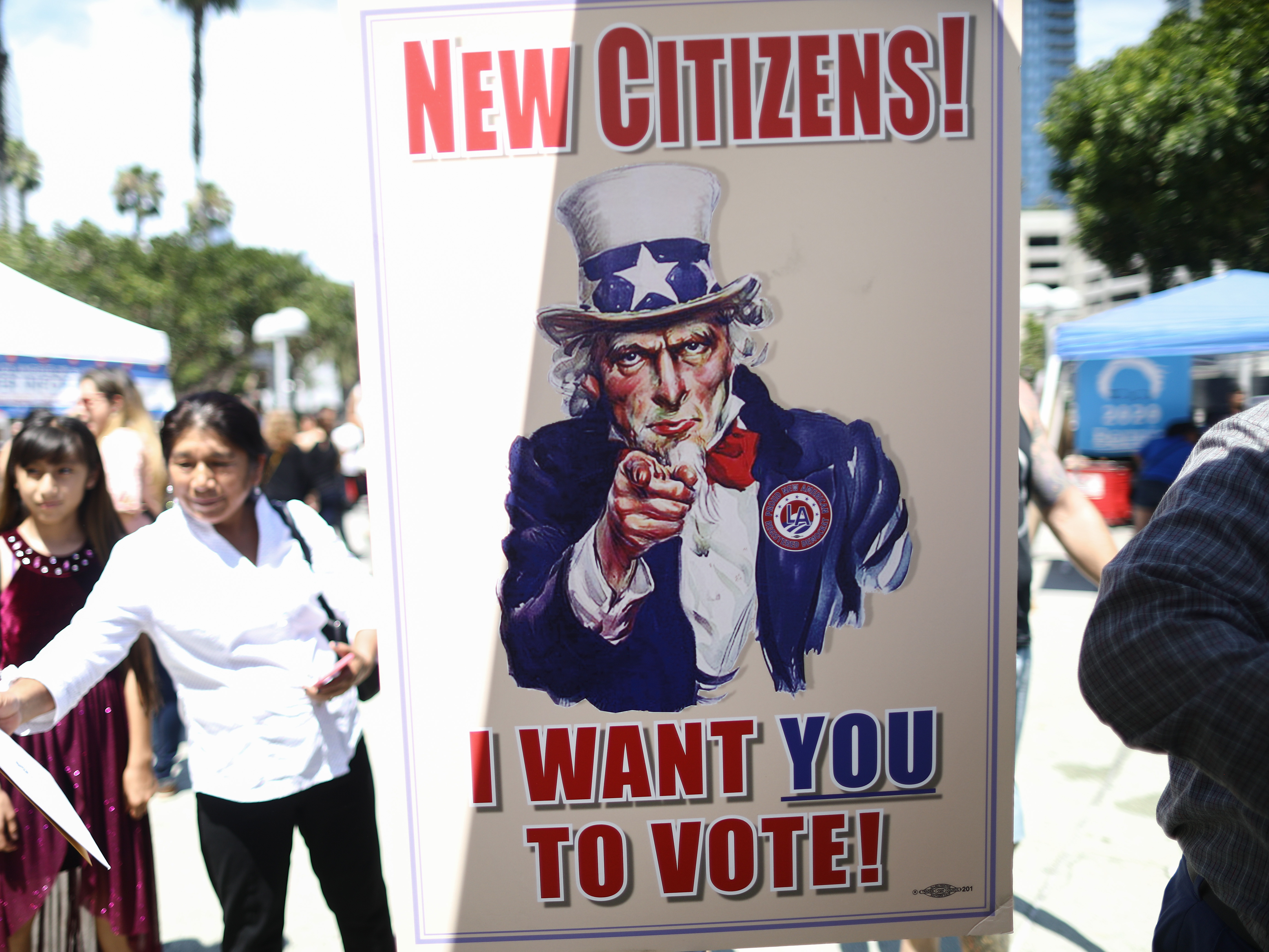 caption: A sign is posted at a voter registration booth outside a naturalization ceremony at the Los Angeles Convention Center on July 23, 2019.