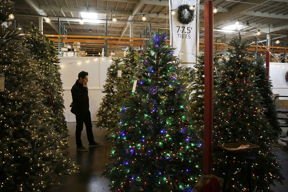 caption: A man looks at artificial Christmas trees for sale at the Balsam Hill Outlet store in Burlingame, Calif,  Nov. 30, 2018. (Eric Risberg/AP)