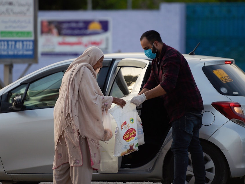 caption: A man donates food to an elderly woman during a government-imposed nationwide lockdown as a preventive measure against the new coronavirus in Islamabad on Sunday.