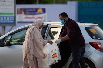 caption: A man donates food to an elderly woman during a government-imposed nationwide lockdown as a preventive measure against the new coronavirus in Islamabad on Sunday.