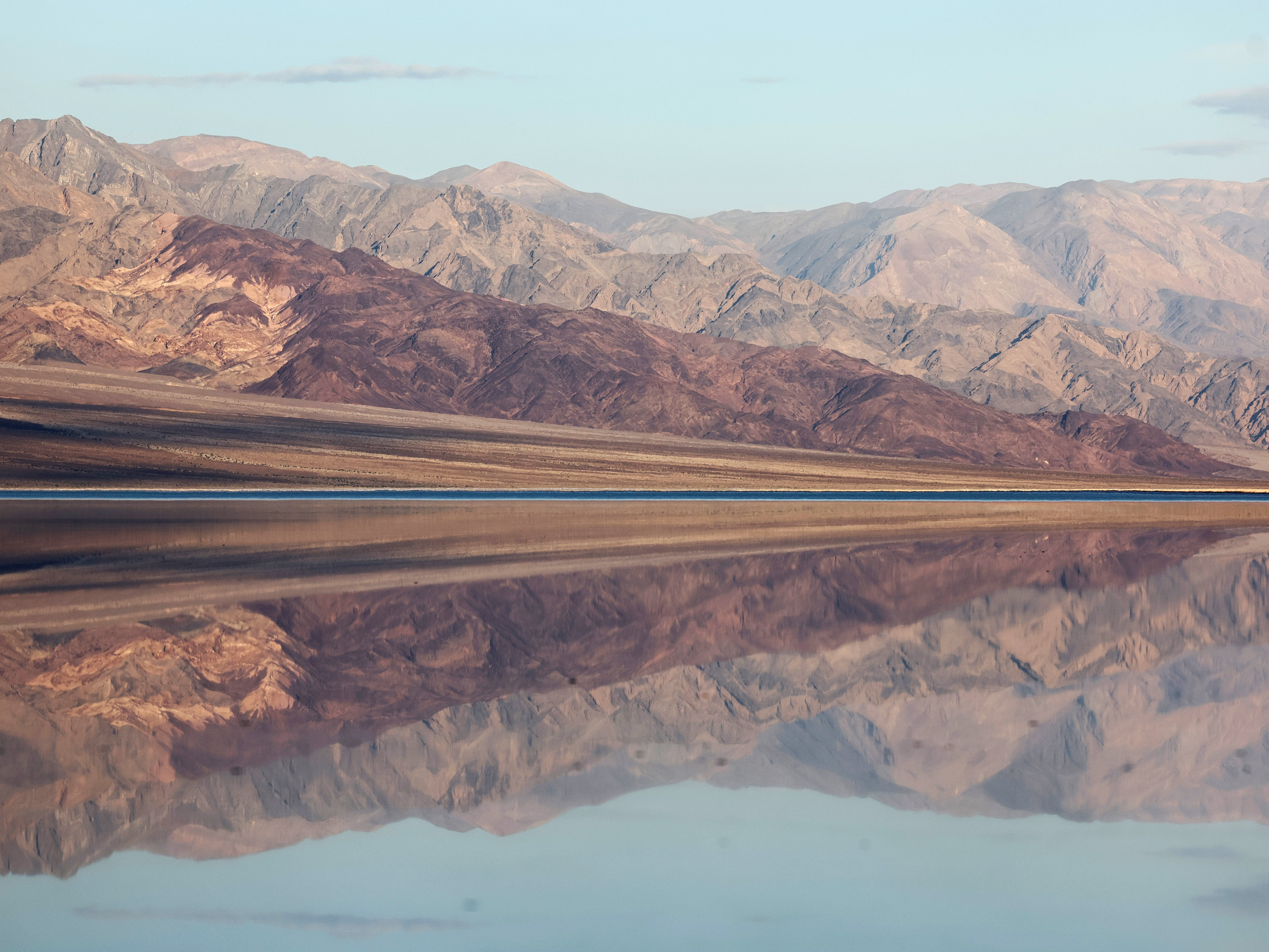 caption: The sun rises beyond the sprawling temporary lake at Badwater Basin salt flats on October 23.