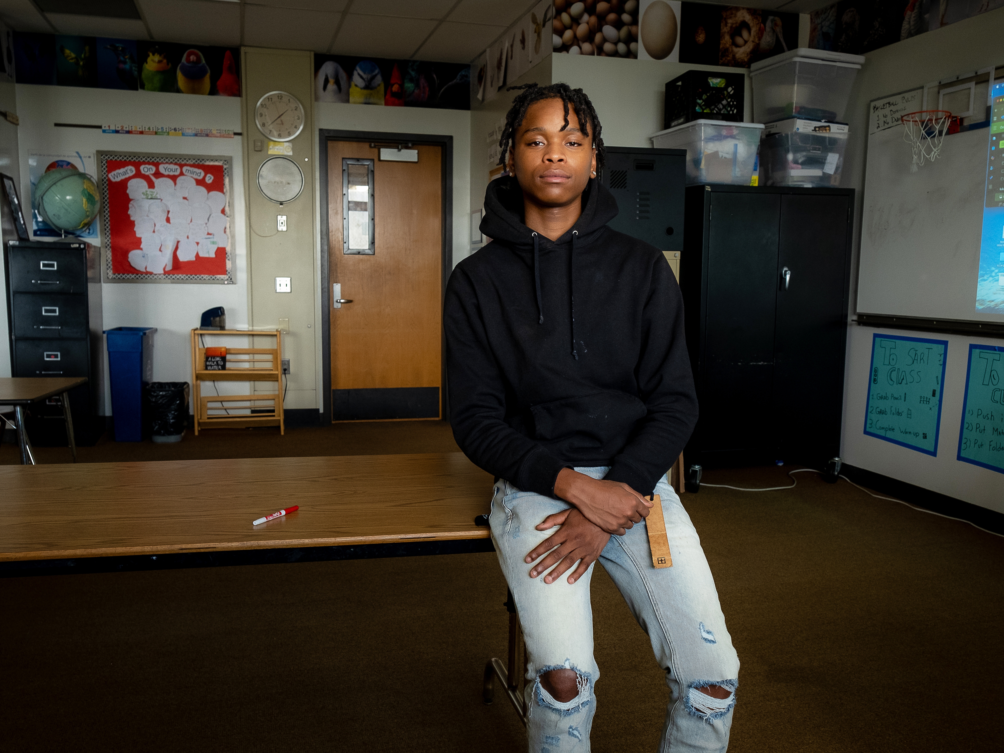 caption: Walter, 19, sits on a desk at Central Senior High School in St. Paul, Minnesota.